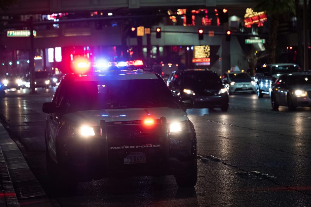 Police SUV with emergency lights activated during a nighttime traffic stop on a busy road.